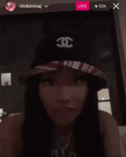 a woman wearing a hat is sitting on a couch in front of a live screen