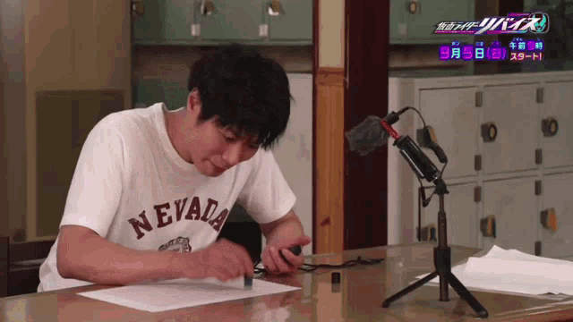a man wearing a nevada t-shirt sits at a desk