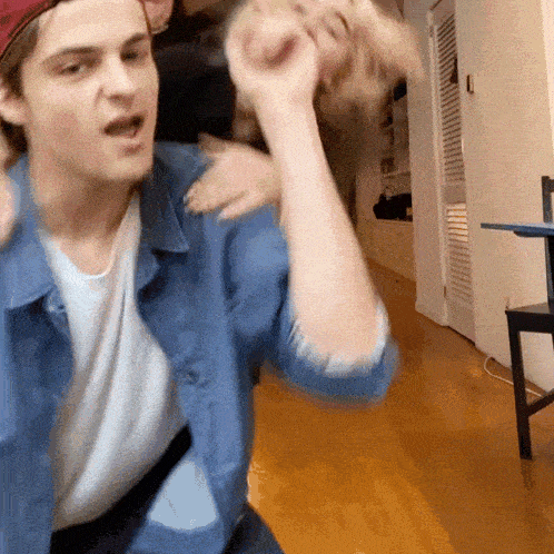 a man in a denim shirt is holding another man 's hand