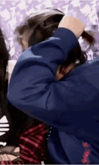 a woman in a blue jacket is holding her hair .