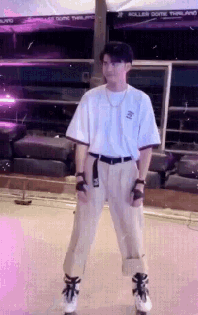 a man wearing a white shirt and khaki pants is standing in front of roller dome thailand