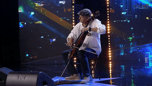 a man playing a cello on a stage with a microphone in the foreground