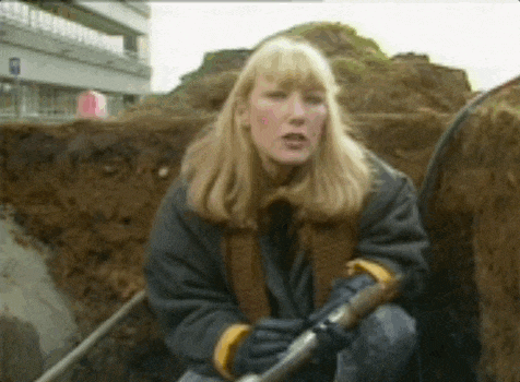 a woman is kneeling down with a shovel in her hands
