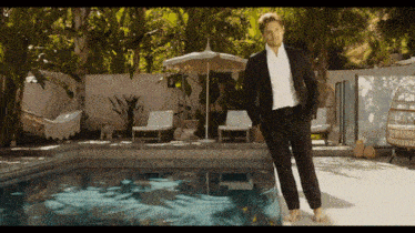 a man in a suit is standing next to a pool