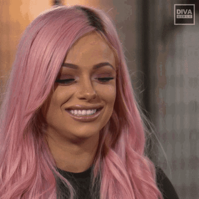 a woman with pink hair is smiling in front of a diva sign
