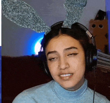 a young woman wearing headphones and bunny ears is making a funny face .