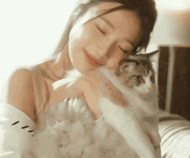 a woman is holding a cat in her arms and smiling at the camera .