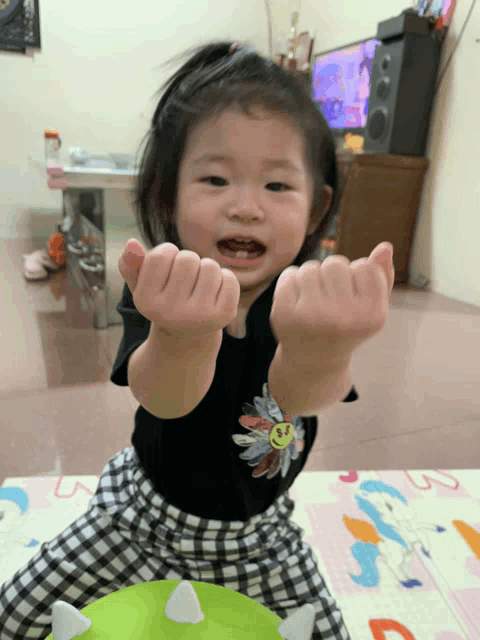 a little girl wearing a black shirt with a bird on it is making a fist