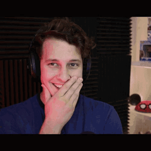 a man wearing headphones and a blue shirt is smiling