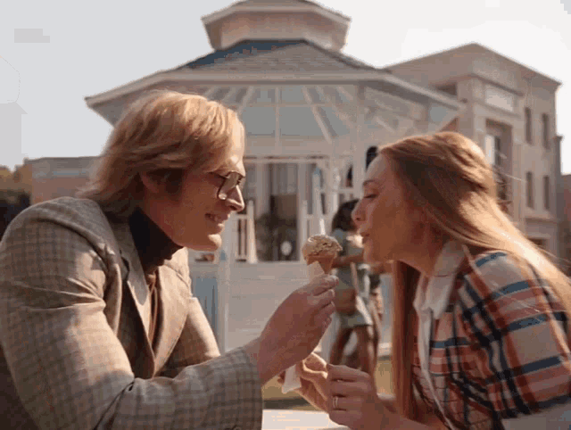 a man is feeding ice cream to a woman