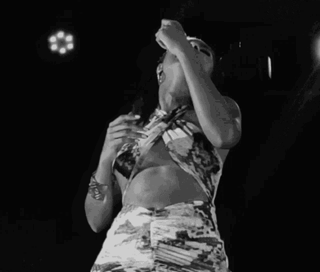 a black and white photo of a woman singing into a microphone while wearing a bracelet that says ' peace '