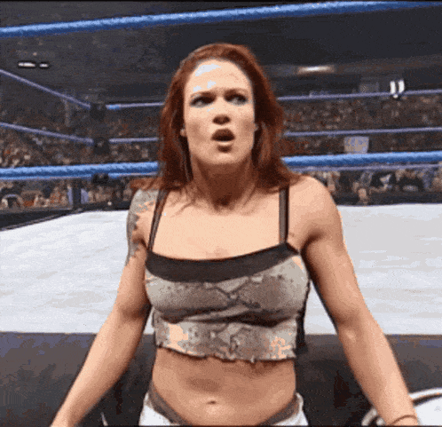 a woman is standing in a wrestling ring with a surprised look on her face
