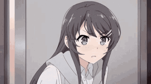 a girl with long hair and blue eyes is standing in front of a door and looking at the camera .
