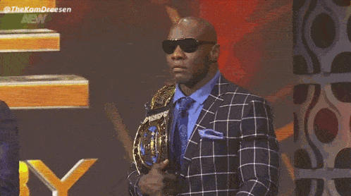 a man in a suit is holding a world heavyweight championship