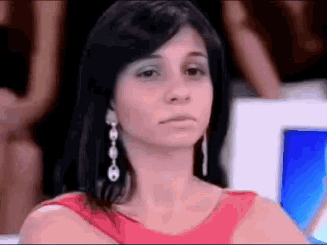 a woman wearing a red dress and earrings is making a funny face
