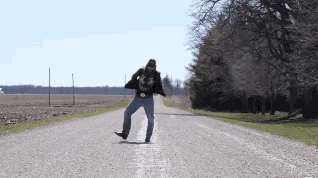 a man is standing on the side of a road in the middle of a field