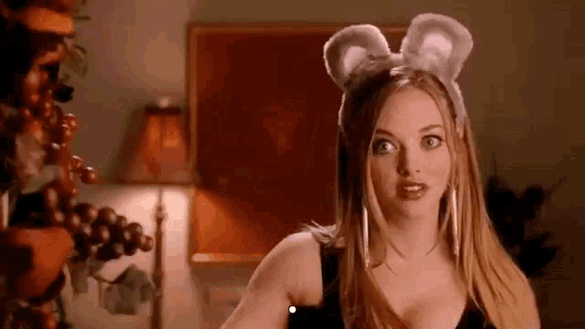 a woman wearing bunny ears and a black top is standing in a room .