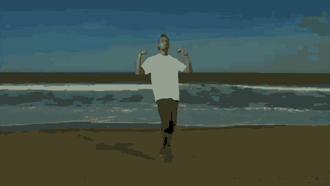 a man is standing on the beach with his arms outstretched .