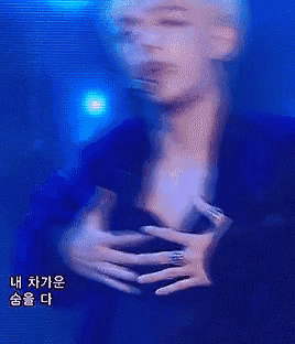 a young man with blonde hair is holding his chest while wearing a microphone .