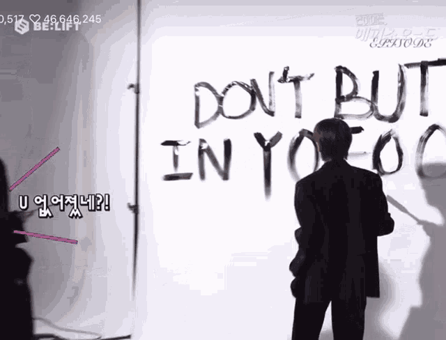 a man is standing in front of a wall that says " don t but in you "