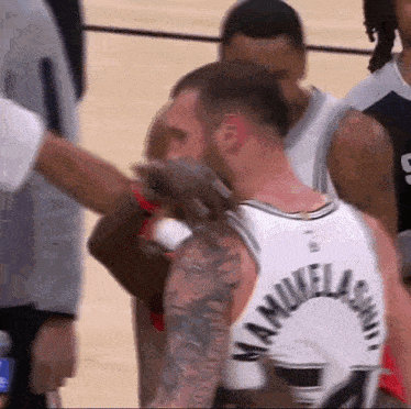 a basketball player with a tattoo on his arm is being helped by a referee .