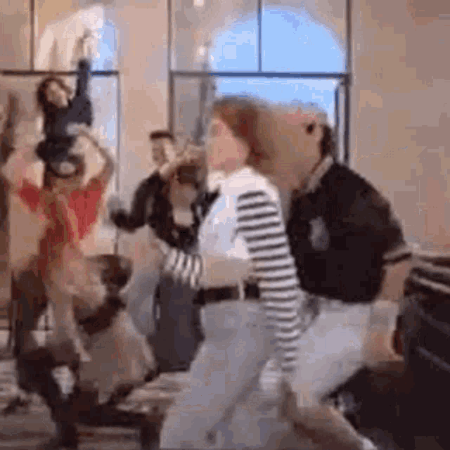 a group of people are dancing in a room with a window in the background .