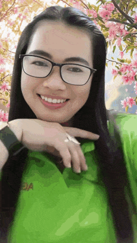 a woman wearing glasses and a green shirt with the letter oa on it