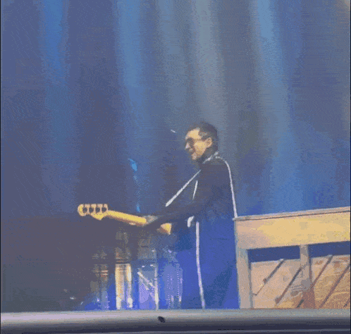 a man is playing a bass guitar and singing into a microphone on stage .