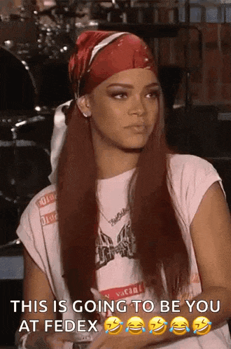 a woman with long red hair wearing a red bandana and a white shirt is sitting in front of a drum set .