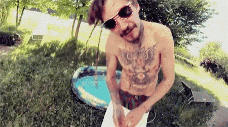 a shirtless man with a tattoo on his chest is standing in front of a small pool