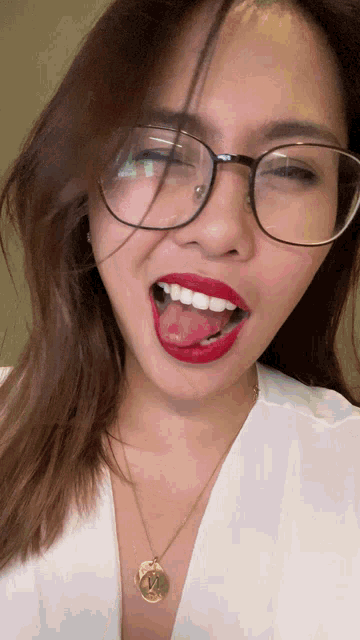 a woman wearing glasses and a necklace with the letter x on it