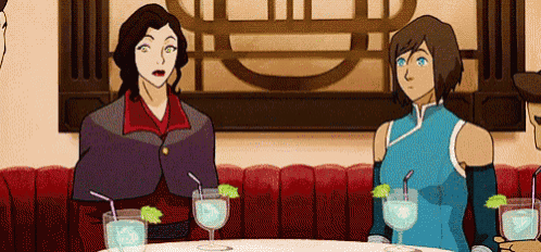 two women are sitting at a table with drinks in their hands .