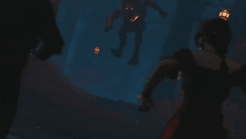 a woman in a black dress is standing in front of a monster