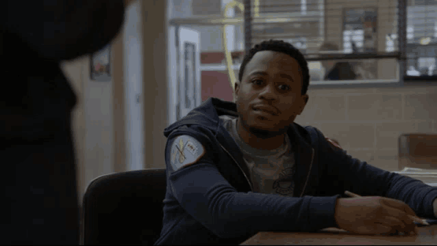 a man sits at a desk with a patch on his sweatshirt that says chicago