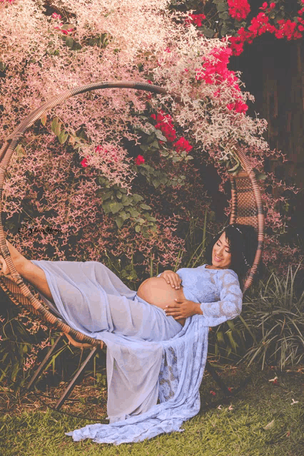 a pregnant woman in a blue dress is sitting in a hanging chair