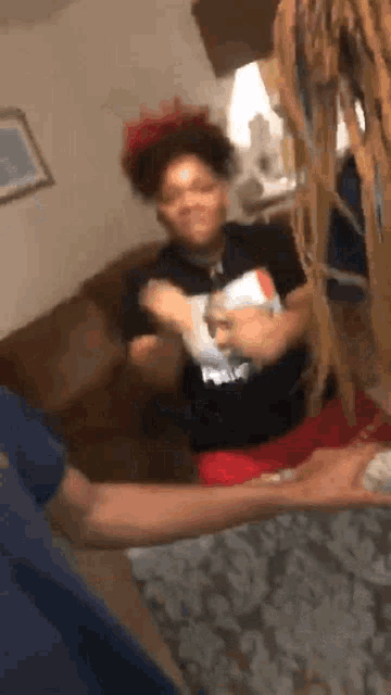 a woman with dreadlocks is dancing in a living room while a man holds her arm .