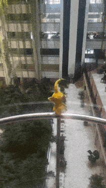 a yellow statue of a bird is sitting on a railing in a building