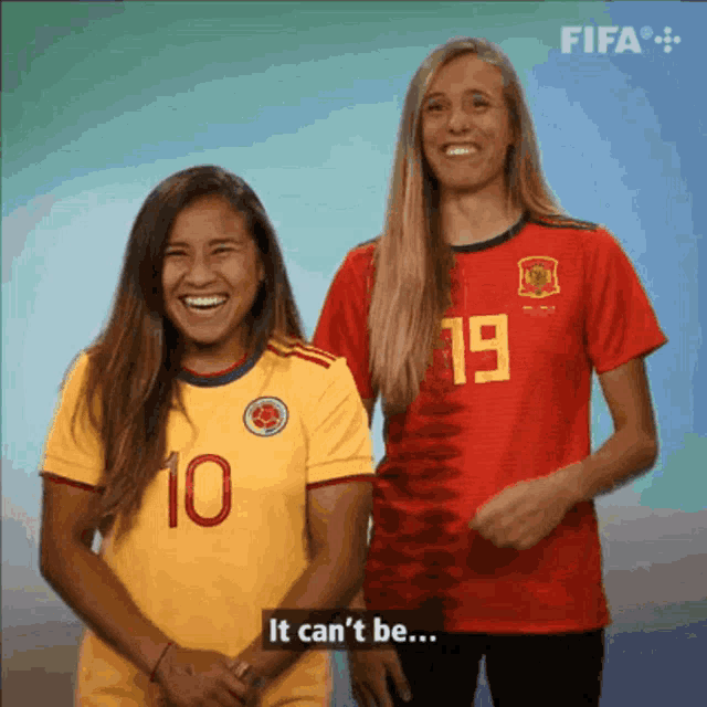a woman wearing a yellow jersey with the number 10 stands next to another woman wearing a red jersey with the number 19