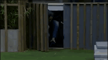 a man is peeking through a wooden fence into a room