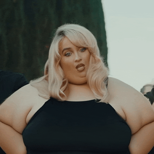 a woman with blonde hair and a black dress is making a face