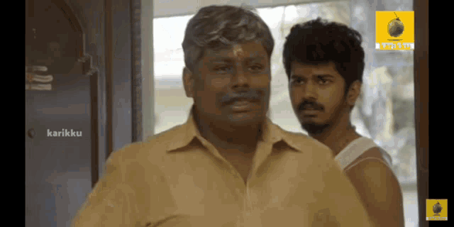 two men are standing in front of a sign that says ' karikku '