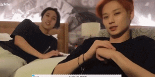 two young men are laying on a bed and one of them has a sticker on his shirt that says ' a '