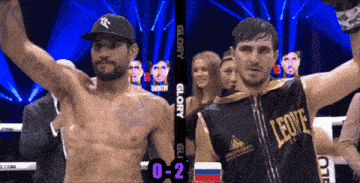 a man in a leone shirt stands next to another man in a boxing ring