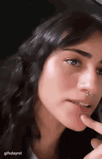 a close up of a woman 's face with a nose ring on her nose .