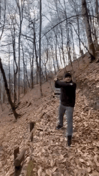 a man in a black jacket is walking through a forest