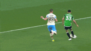 soccer players on a field with a goalie wearing a green jersey with the number 23 on it