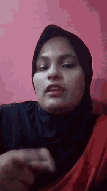 a woman wearing a hijab is making a funny face .