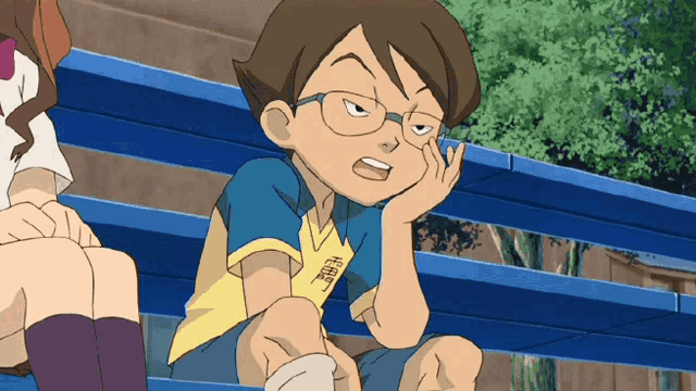 a boy wearing glasses and a yellow shirt with chinese characters on it sits on a bench