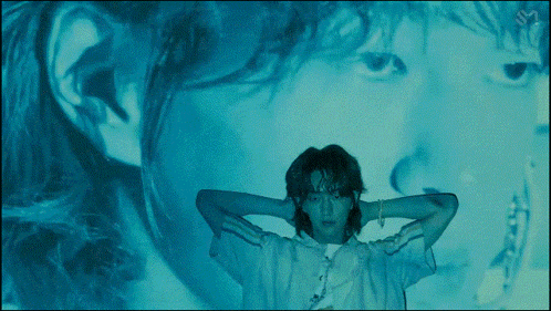 a man is standing in front of a projection of a woman 's face with the letter s on it