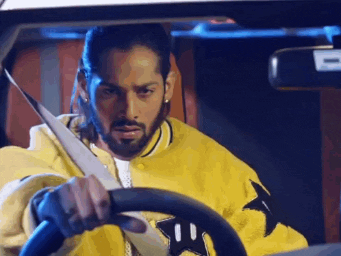 a man in a yellow jacket is driving a car and putting on his seat belt